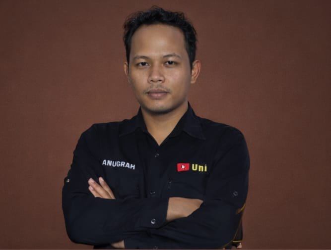 Gajah berjalan di rumput keemasan saat matahari terbenam.